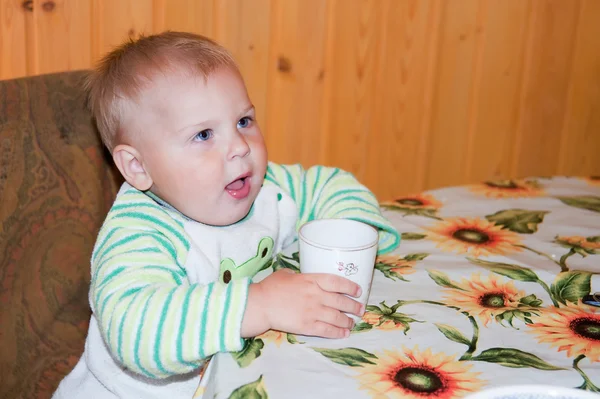 Little boy is drinking at a table — Stock Photo, Image