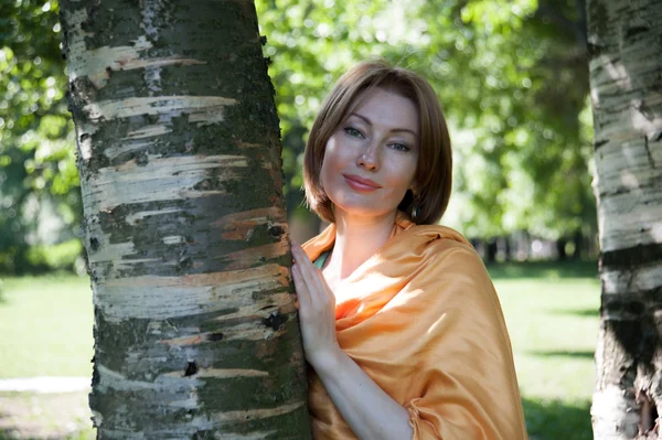 Beautiful woman at a tree in summer — Stock Photo, Image