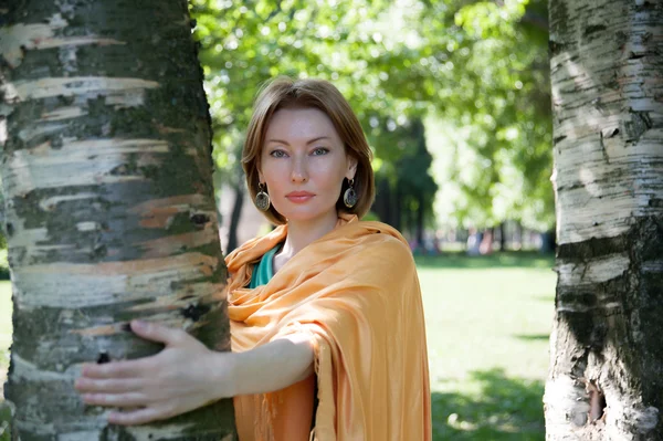 Schöne Frau an einem Baum im Sommer — Stockfoto