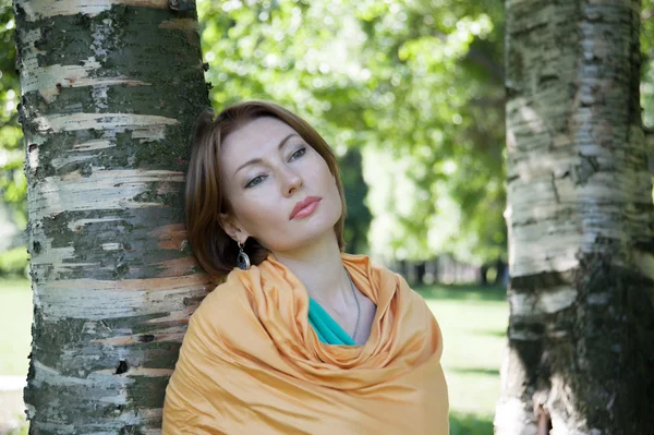 Schöne Frau an einem Baum im Sommer — Stockfoto