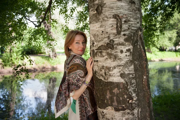 Schöne Frau an einem Baum im Sommer — Stockfoto