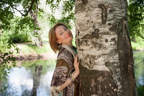 Mooie vrouw op een boom in de zomer — Stockfoto