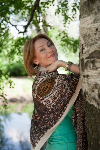 Beautiful woman at a tree in summer — Stock Photo, Image