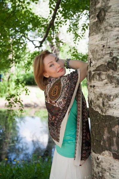 Mooie vrouw op een boom in de zomer — Stockfoto