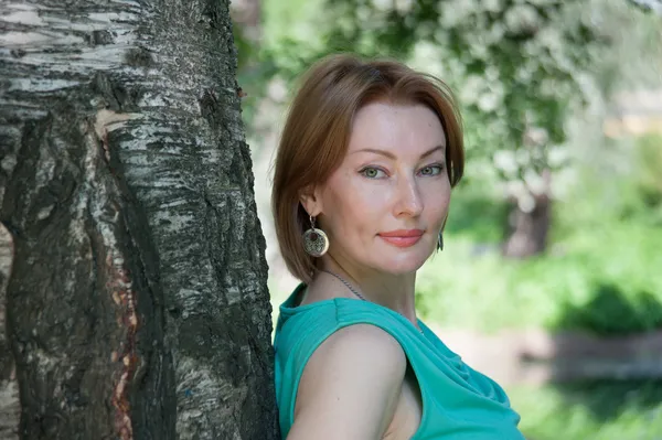 Beautiful woman at a tree in summer — Stock Photo, Image