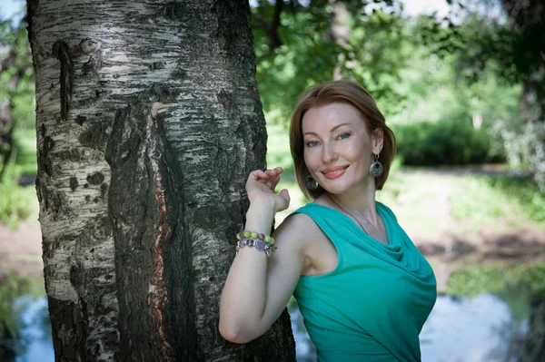 Beautiful woman at a tree in summer — Stock Photo, Image