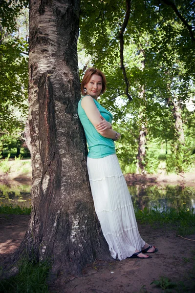 Beautiful woman at a tree in summer — Stock Photo, Image