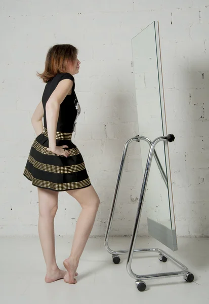 Frau schaut in Spiegel, probiert Kleid aus — Stockfoto