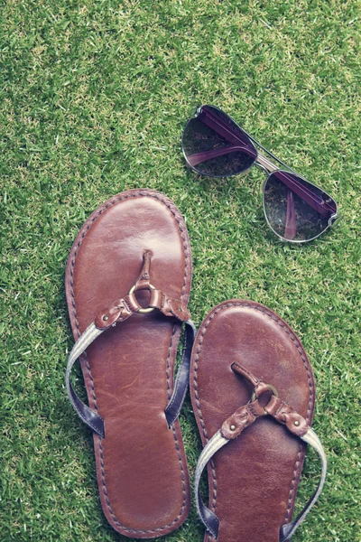 Sandalias de verano y gafas de sol sobre hierba — Foto de Stock