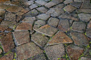 Yüzey yosunlarla kaplı farklı boyutlarda eski taşlarla kaplı.