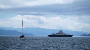 Yat yelken açar deniz ve gemi tepelere karşı dalgalar üzerinde sürüklenir.