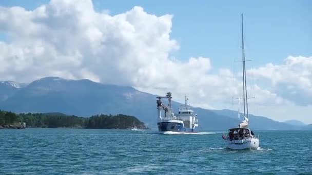 Jacht zeilt zee voorbij vrachtschip tegen fjord bergen — Stockvideo