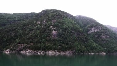 Eski eğimli dağlar ve sakin deniz koyunun fiyort kıyıları