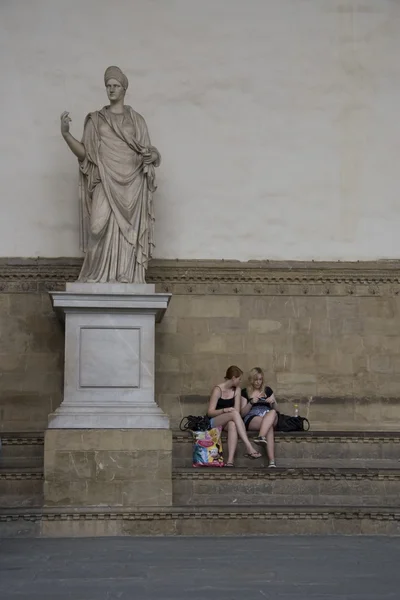 동상 옆에 앉아 있는 소녀들 — 스톡 사진