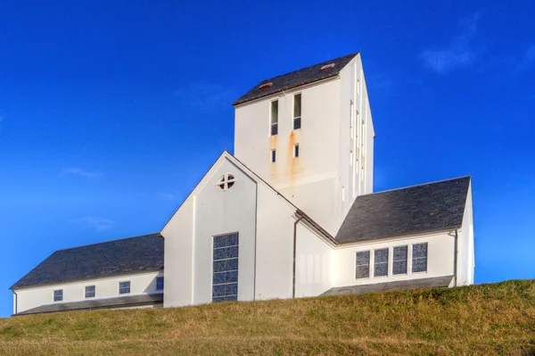 Weiße Kirche auf einem grasbewachsenen Hügel — Stockfoto