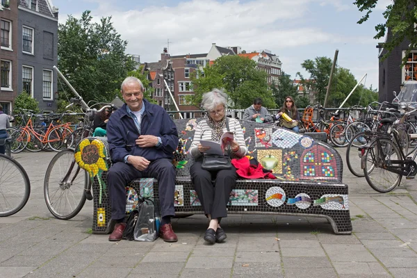 Amsterdam, Netherlands: June 14, 2012 - older couple sitting on bench in Amsterdam — Stock Photo, Image