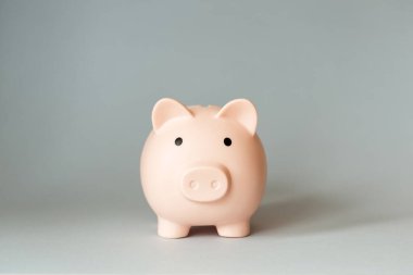 Gri arka planda, kopyalama alanı olan bir kumbara. Yatırım, mevduat ve tasarruf için banka hesapları. asgari kavram.