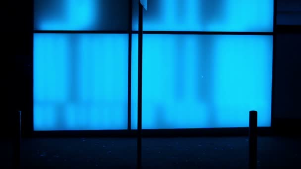 Silhouetten voor een blauw verlichte glazen muur — Stockvideo