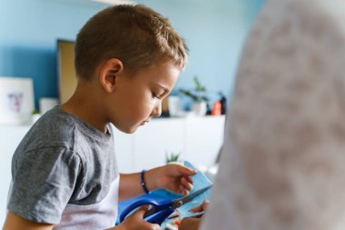 Evinde kumaş kesen dört yaşındaki küçük beyaz çocuk hakkında ön görüş - küçük çocuk makasla oynuyor yaratıcı işler geliştiriyor - gelişim çağında gerçek insanlar eğlence aktivitesi kavramı