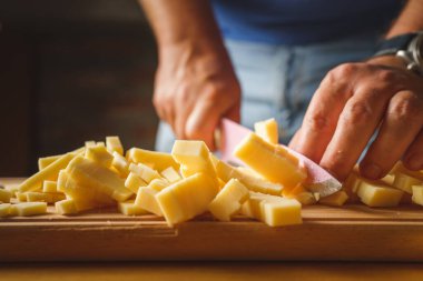 Bıçakla tahtadan peynir kesen tanımadığımız bir adamın ellerine yaklaş.