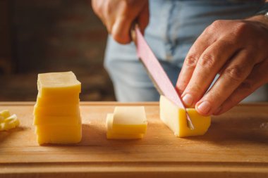 Bıçakla tahtadan peynir kesen tanımadığımız bir adamın ellerine yaklaş.