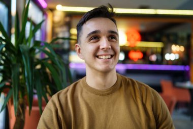 Kafenin önünde oturan beyaz bir adam gülümseyen mutlu bir erkek.