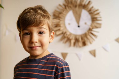Evinin önündeki küçük beyaz çocuğun portresi fotokopi odası duvarın önünde duruyor ve kameraya bakıyor.