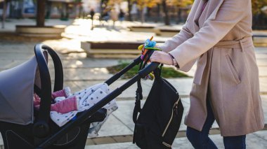 Bilinmeyen Kafkasyalı kadının karnına yaklaşın. Annesi bebeğiyle bebek arabasını gündüz vakti şehirde itiyor. Annelik kavramı.