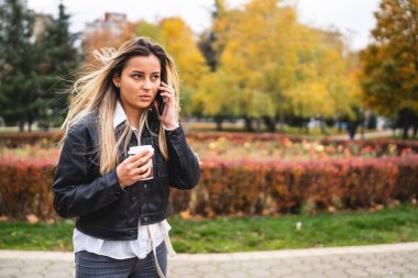 Sonbaharda ya da kış günü dışarıda park etmiş genç beyaz bir kadın cep telefonuyla konuşuyor. Kötü haberler alıyor. Elinde bir fincan kahve tutuyor.