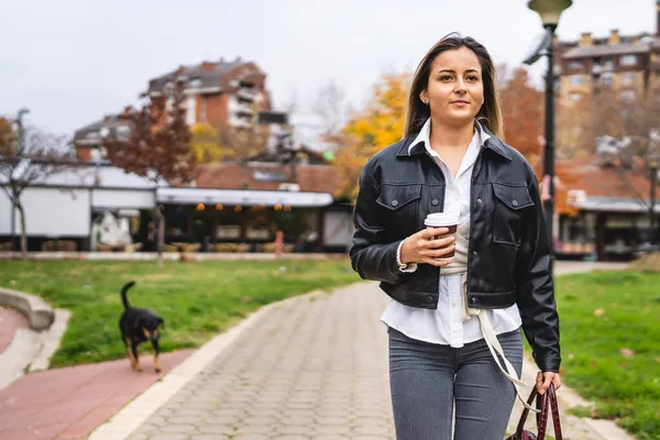 一个年轻的高加索女人在公园里散步 后面跟着一只狗的前视图画像 真实的人复制空间 — 图库照片