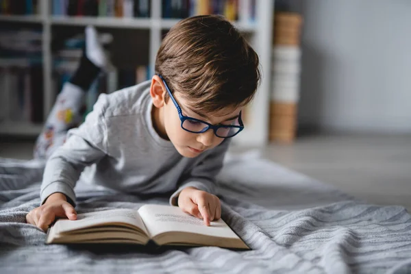 一人の白人少年が家の床に横になって本を読んでフロントビューコピースペース現実の人々の教育の概念 — ストック写真