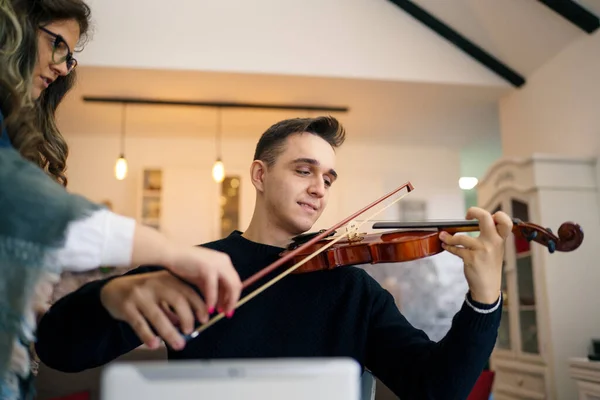 一人で部屋で彼のアパートで音楽を演奏するバイオリン男性バイオリニストを再生するために自宅学習で椅子に座っている若い大人の白人男性 — ストック写真