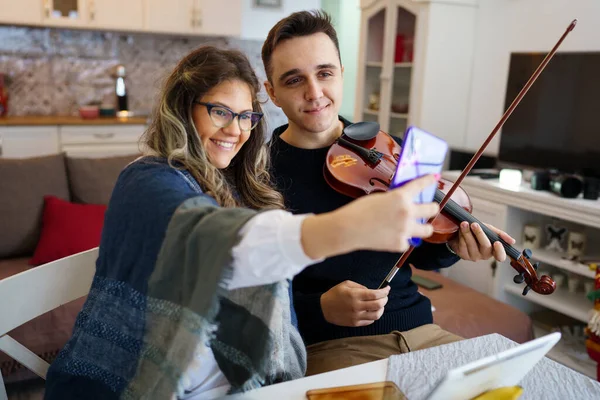 커플이나 친구들은 집에서 테이블에 사진을 찍거나 바이올린을 행복하게 모습으로 비디오 — 스톡 사진