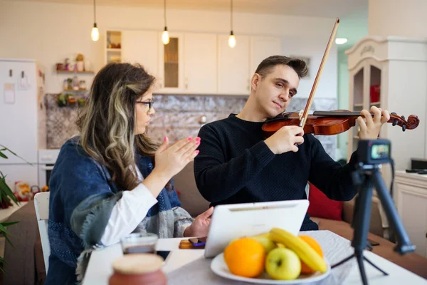 若い大人の白人男性学生は 彼の教授の女性の指導者の助けを借りてバイオリンを学ぶ家庭でスキルを向上させる方法を彼に教える実際の人々のプライベートクラスの概念を説明する — ストック写真