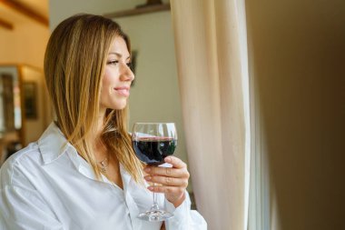 Güzel esmer beyaz kadın portresi elinde bir bardak kırmızı şarapla ayakta dikiliyordu. Pencereden bakıyordu. Restoranda ya da evde güler yüzlü beyaz gömlekli fotokopi odası vardı.