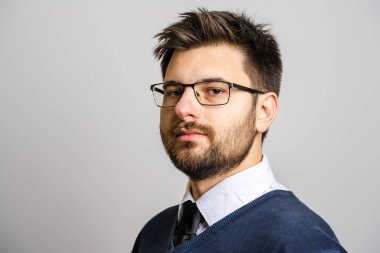 30 yaşında, sakallı, gözlüklü, beyaz arka planda kameraya bakan genç bir beyaz adamın portresi. Süveter giyen genç iş adamı başarısı konsepti.