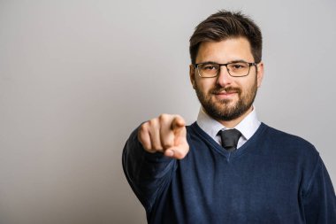 30 yaşında, sakallı, gözlüklü, beyaz arka planda kameraya bakan beyaz bir beyaz adamın portresi kameranın kendine güvenen konseptini taklit ediyor.