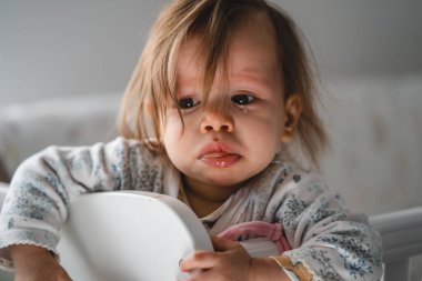 Küçük beyaz bir bebeğin portresini kapat beşikteki beşik yatağında dikilip ağlayan yaralı ve üzgün gözlerle gün içinde tek başına ağlayan