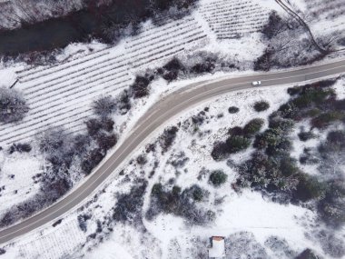 High angle top down aerial view drone image on road trough the trees and forest covered with white snow in winter day near Knjazevac in Serbia Car drive Travel journey and vacation concept