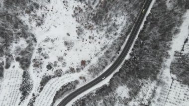 Seyahat yolculuğu ve tatil konsepti Sırbistan 'ın Knjazevac kenti yakınlarında kış günü beyaz karla dağlık alanda giden kıvrımlı serpentin yol aracının yüksek açılı hava aracı videosu