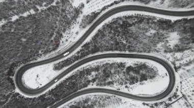 Seyahat yolculuğu ve tatil konsepti Sırbistan 'ın Knjazevac kenti yakınlarında kış günü beyaz karla dağlık alanda giden kıvrımlı serpentin yol aracının yüksek açılı hava aracı videosu