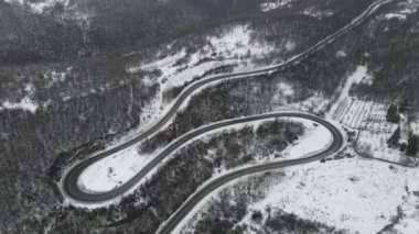 Seyahat yolculuğu ve tatil konsepti Sırbistan 'ın Knjazevac kenti yakınlarında kış günü beyaz karla dağlık alanda giden kıvrımlı serpentin yol aracının yüksek açılı hava aracı videosu