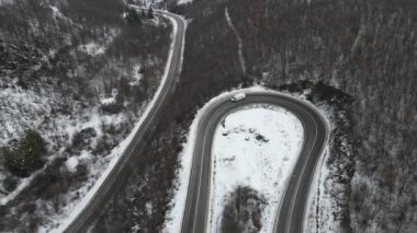 Seyahat yolculuğu ve tatil konsepti Sırbistan 'ın Knjazevac kenti yakınlarında kış günü beyaz karla dağlık alanda giden kıvrımlı serpentin yol aracının yüksek açılı hava aracı videosu
