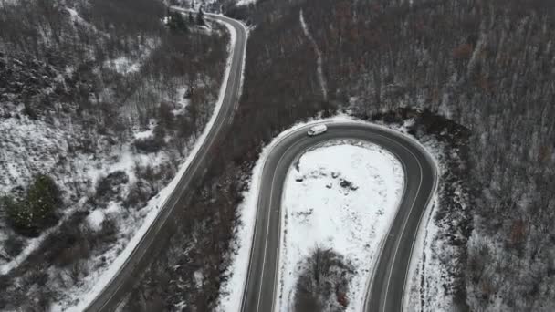 旅行の旅と休暇のコンセプトセルビアのKnjazevac近くの冬の日に白い雪と山の範囲で運転サーペンタイン道路の車の曲線上の高角度の空中ビュードローンビデオ — ストック動画
