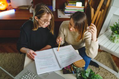 two women young caucasian female student sitting at home with her mentor teacher looking to the notebook explaining lesson study preparing for exam learning education concept real people copy space