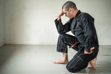 Yetişkin erkek atlet Bjj Brezilyalı jiu jistu siyah kuşak, beyaz duvarın önünde fotokopi aletiyle duruyor.