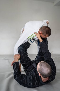 İki Brezilyalı jiu jitsu bjj figörleri dövüş sanatları eğitimi erkek atlet tekniği ya da tatami minderinde siyah beyaz kimono gi üniforması giyerek yedek olmak.