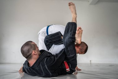 İki Brezilyalı jiu jitsu bjj figörleri dövüş sanatları eğitimi erkek atlet tekniği ya da tatami minderinde siyah beyaz kimono gi üniforması giyerek yedek olmak.
