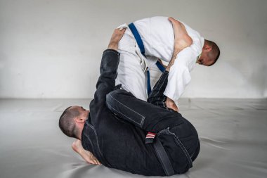 İki Brezilyalı jiu jitsu bjj figörleri dövüş sanatları eğitimi erkek atlet tekniği ya da tatami minderinde siyah beyaz kimono gi üniforması giyerek yedek olmak.