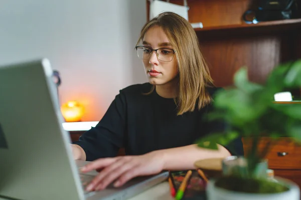 Laptop bilgisayarında çalışan beyaz bir bayan öğrenci evde oturmuş online öğrenim ve eğitim konsepti yazarak test sonuçlarını veya internet alışverişini kontrol ediyor.
